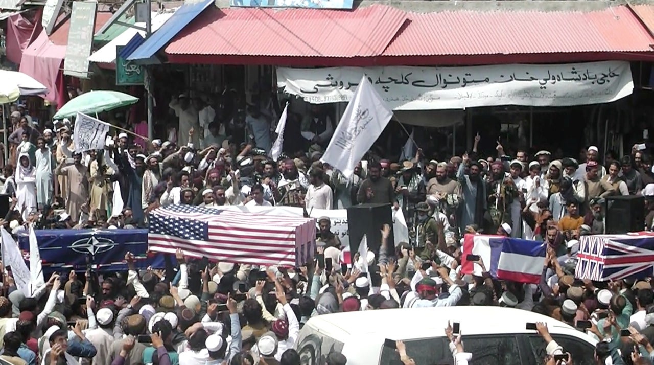 Crowd carries makeshift coffins draped in NATO's, US and a Union Jack flags during a mock funeral on a street in Khost, Afghanistan.