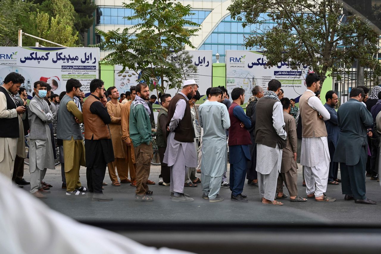Afghans queue up as they wait for the banks to open and operate at a commercial area in Kabul.