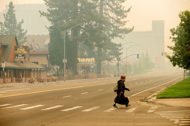 A woman crosses Highway 50 on Tuesday, Aug. 31, 2021, in South Lake Tahoe, Calif., which has been evacuated due to the Caldor Fire's approach. 