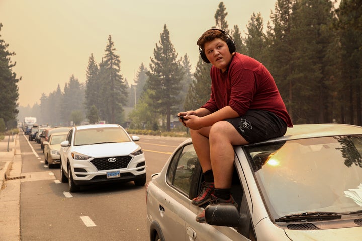  Victor Salas Jr.,15, sits on top of his car as he waits in evacuation traffic on Highway 50 out of South Lake Tahoe, Calif. on Monday, Aug. 30, 2021. Due to the threat of encroaching wildfire flames from the Caldor Fire, evacuation orders were issued Monday afternoon for all of South Lake Tahoe. 