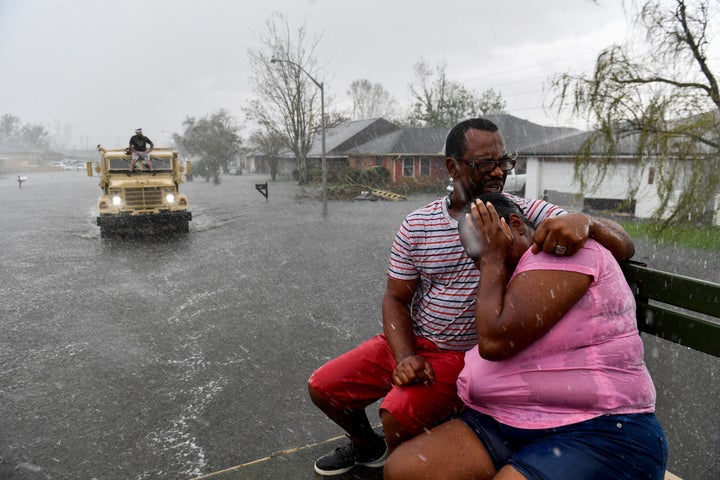 People react as a sudden rain shower soaks them with water while riding out of a flooded neighborhood in a volunteer high water truck assisting people evacuating from homes after neighborhoods flooded in LaPlace, Louisiana on August 30.