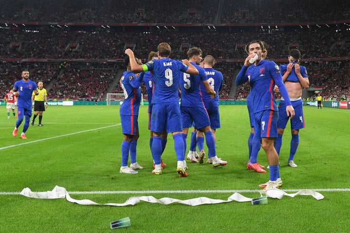 Jack Grealish drinks from a cup thrown from the crowd after Harry Maguire scores the third goal during the 2022 FIFA World Cup qualifier in Budapest.