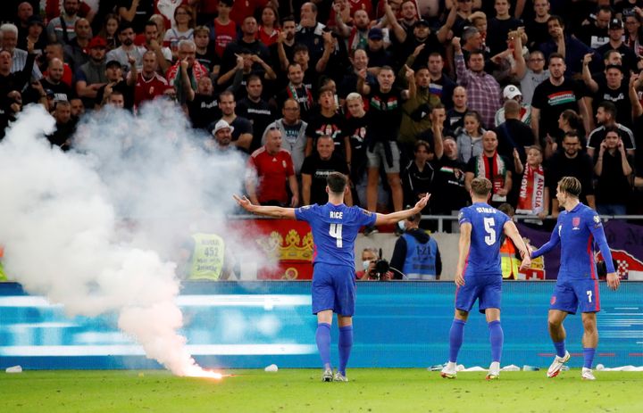 Declan Rice, John Stones and Jack Grealish react after a flare is thrown on to the pitch by Hungary fans after Harry Maguire scored their third goal.