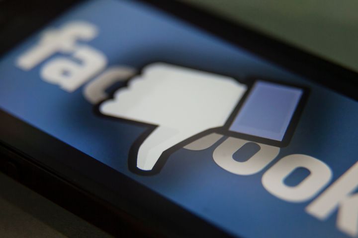 Facebook thumbs-down hand on a iPhone. Facebook is a social media company owned by Mark Zuckerberg. (Photo by Ted Soqui/Corbis via Getty Images)