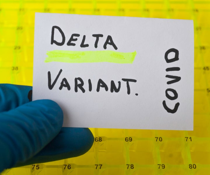 hand with a blue surgical glove holding a sign with the text delta variant in a laboratory