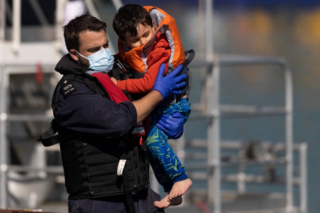 A young migrant being carried by a Border Force official after arriving into Dover on