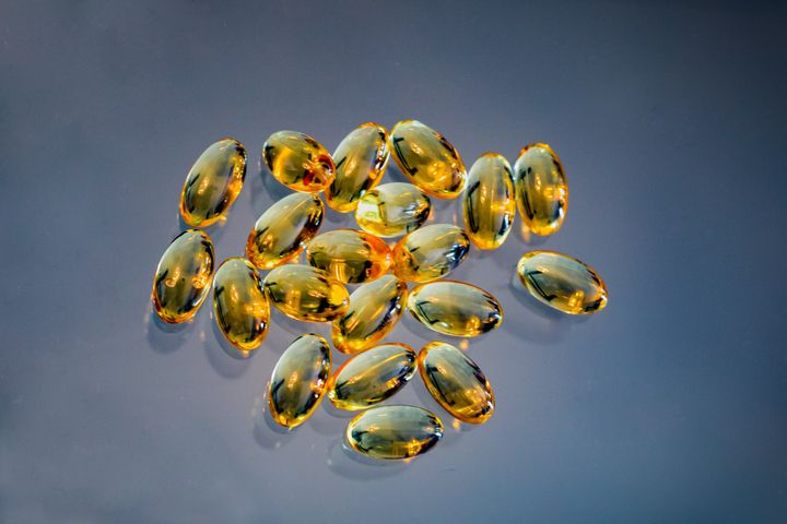 Vitamin D capsules on blue background.