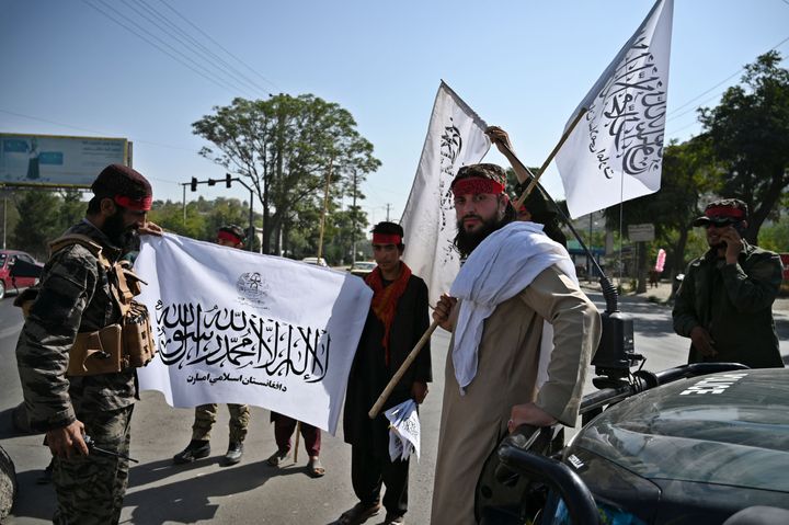 Μαχητές των Ταλιμπάν κρατούν σημαίες των Ταλιμπάν ενώ φρουρούν κατά μήκος ενός δρόμου στην Καμπούλ