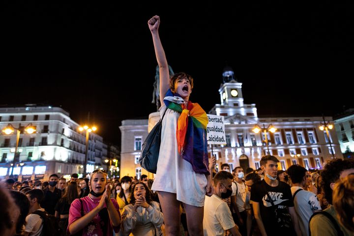 Una mujer alza el puño en Sol (Madrid) ataviada con la bandera arcoiris, este viernes, tras conocerse que la denuncia del joven de Malasaña es falsa