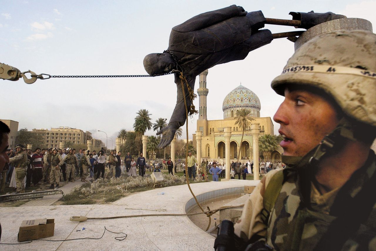 Ιρακινοί πολίτες και Αμερικανοί στρατιώτες κατεβάζουν άγαλμα του Σαντάμ Χουσέιν στην Βαγδάτη, στις 9 Απριλίου 2003. 