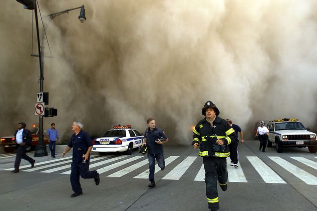 Policemen and firemen run away from the huge dust cloud caused as the World Trade Centre collapses.