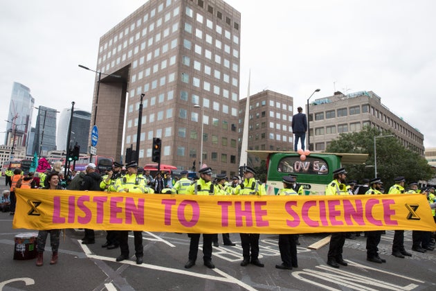 Environmental activists from Extinction Rebellion hold a banner calling on the government to cease all...