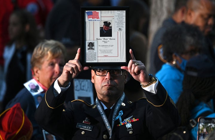 A firefighter holds up the image of a 9/11 victim as people attend a ceremony commemorating the 20th anniversary.