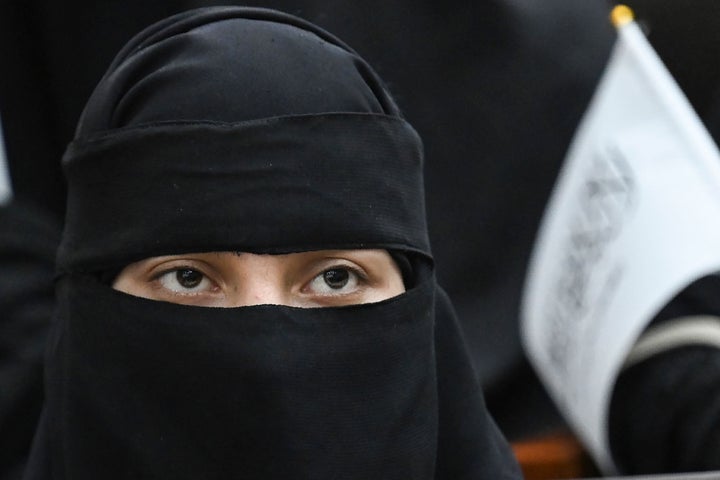 A veiled student holds a Taliban flag while listening to a speaker before a pro-Taliban rally at the Shaheed Rabbani Education University in Kabul on September 11.