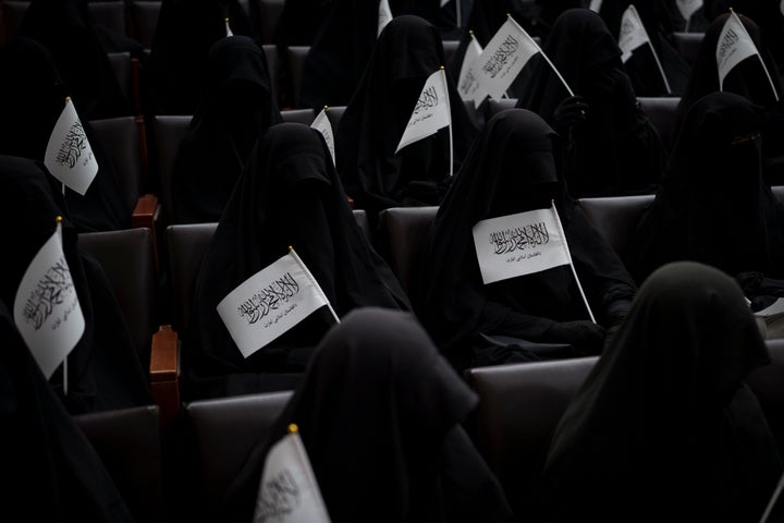 Women wave Taliban flags as they sit inside an auditorium at Kabul University's education center during a demonstration in support of the Taliban government on Sept. 11.