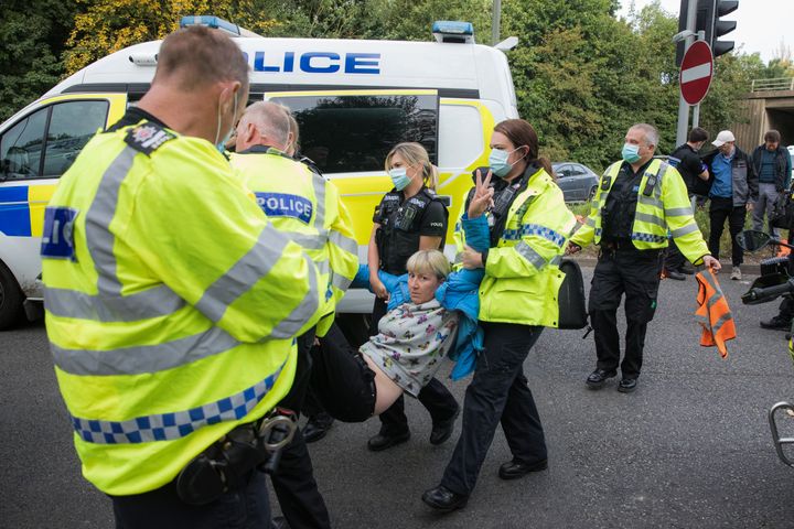 Police officers arrest an Insulate Britain climate activist who had been blocking a slip road from the M25 on Monday
