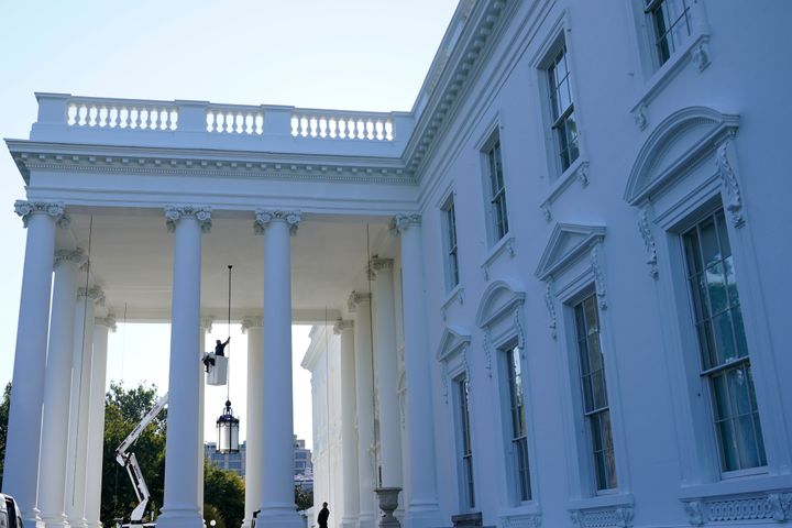 A worker works on the light fixture over the North Portico of the White House in Washington, Friday, Sept. 3, 2021. (AP Photo/Susan Walsh)