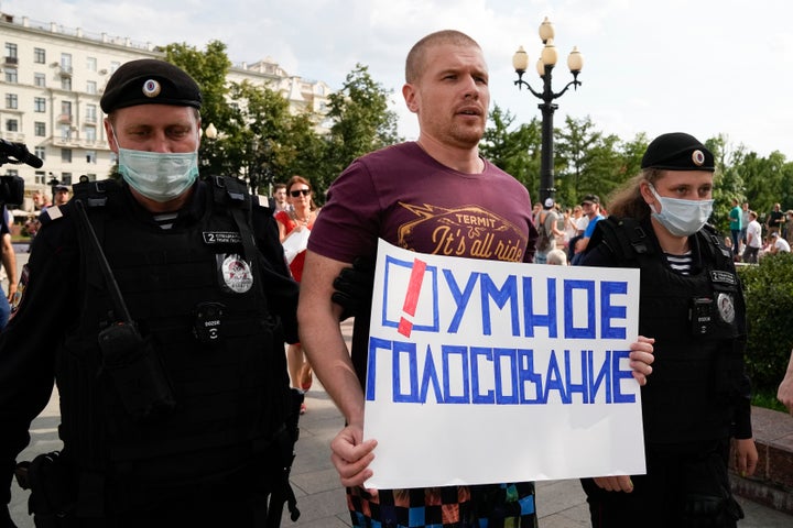 Russian police detain an opposition activist with a poster reading "Smart voting" during an anti-vaccination protest in the center of Moscow, Russia, Saturday, Aug. 14, 2021. (AP Photo/Alexander Zemlianichenko)