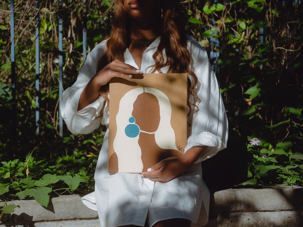 Tally Dilbert poses with one of the portraits she created of Black and brown women.