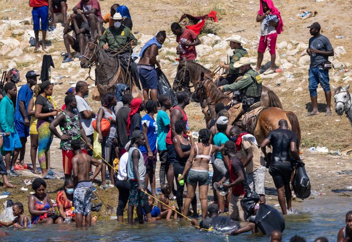 US border patrol agents interact with Haitian immigrants on the bank of the Rio Grande in Del Rio, Texas on Monday