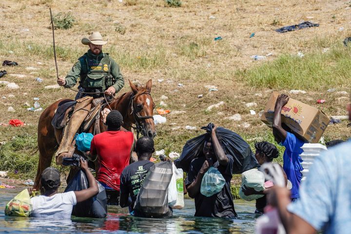 A US Border Patrol agent on horseback uses the reins as he tries to stop Haitian migrants