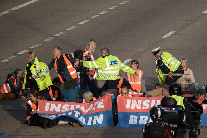 Surrey Police officers try to remove Insulate Britain climate activists from the carriageway.