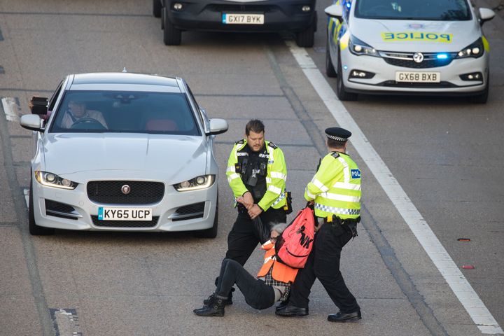 Surrey Police officers haul an Insulate Britain climate activist from the carriageway of the M25.