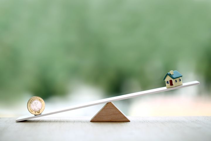 Indian rupee coin and miniature balancing on seesaw