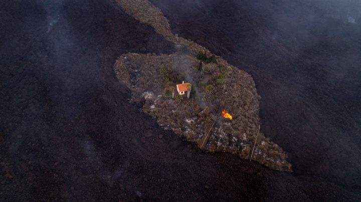 Σε αυτή τη φωτογραφία που παρέχεται από το iLoveTheWorld, ένα σπίτι παραμένει άθικτο καθώς η λάβα ρέει μετά από έκρηξη ηφαιστείου κοντά στο Las Manchas στο νησί La Palma στα Κανάρια Κανάρια, Ισπανία, Δευτέρα, 20 Σεπτεμβρίου 2021.