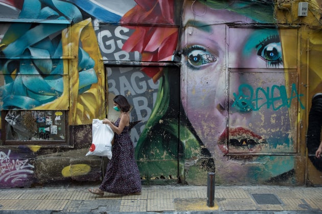 A woman seen passing in front of a graffiti in the center of Athens, Greece on September 16, 2021. (Photo by Nikolas Kokovlis/NurPhoto via Getty Images)