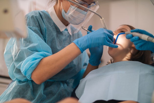 Close up of unrecognizable female dentist doing examination on a little girl in dentist clinic.
