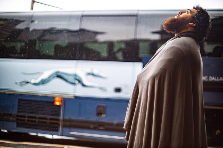 A passenger at a Greyhound bus terminal waits for a mechanic to fix a bus's flat tire on July 14, 2021.