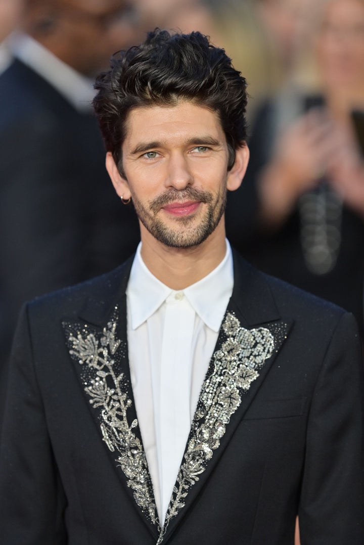 Ben Whishaw, in a jeweled jacket, smiles for the cameras. 