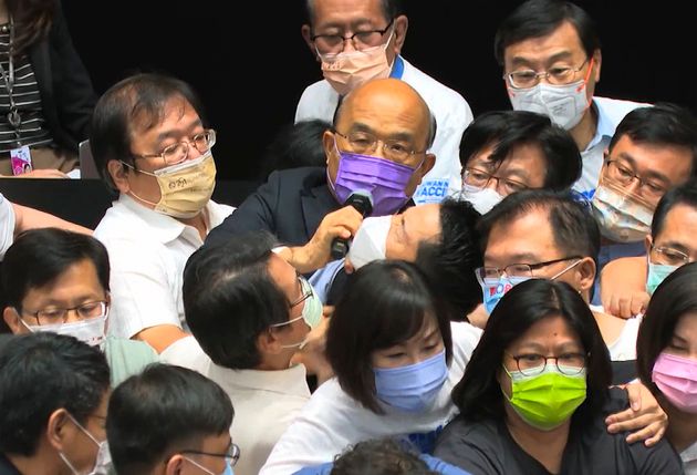 Ο πρωθυπουργός Σου Τσενγκ Τσανγκ φορώντας μωβ μάσκα, προσπαθεί να ολοκληρώσει την ομιλία του.