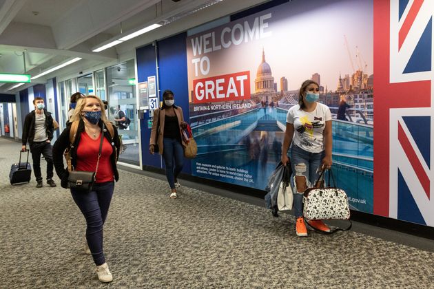 Passengers in protective face masks are seen arriving at London Stansted Airport as the airline industry...
