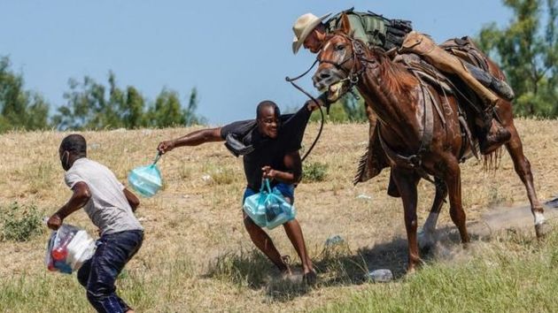 Agentes fronterizos a caballo, persiguiendo y cargando contra migrantes haitianos cerca del río...