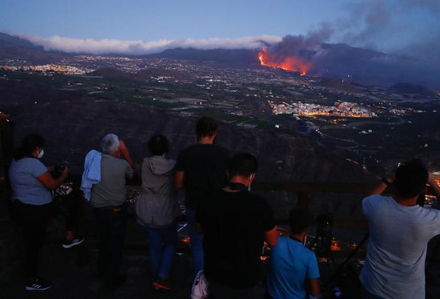 People watch lava flowing after the eruption of a volcano on the Canary Island of La Palma, as seen from...