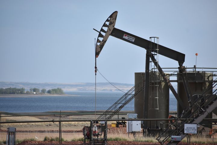 A pump jack extracts oil from beneath the ground on the Fort Berthold Indian Reservation, with Lake Sakakawea in the backgrou