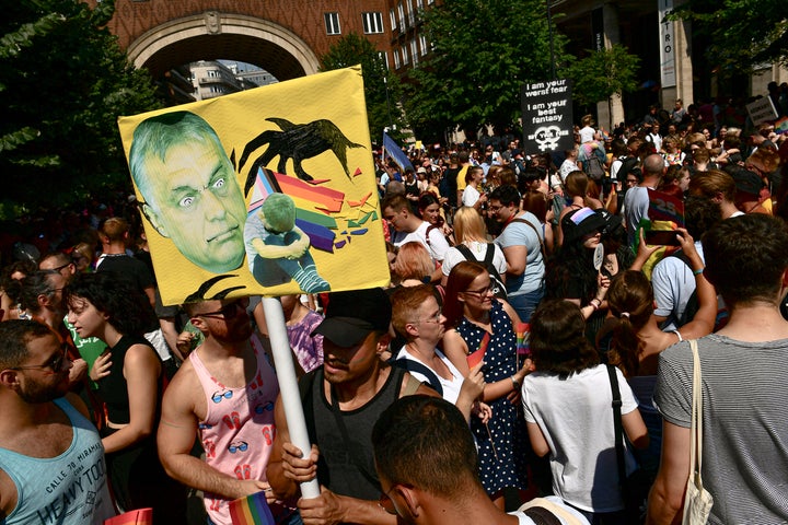 People taking part in a gay pride parade hold a banner depicting Hungarian Prime Minister Viktor Orbán in Budapest, Hungary, on July 24, 2021. Hungary's government passed a law in June prohibiting the display of content depicting homosexuality or gender reassignment to minors, a move that ignited intense opposition in Hungary while EU lawmakers urged the European Commission to take swift action against Hungary.