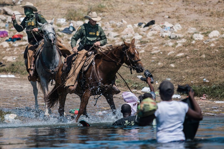 U.S. Customs and Border Protection mounted officers attempt to contain migrants as they cross the Rio Grande from Ciudad Acuñ