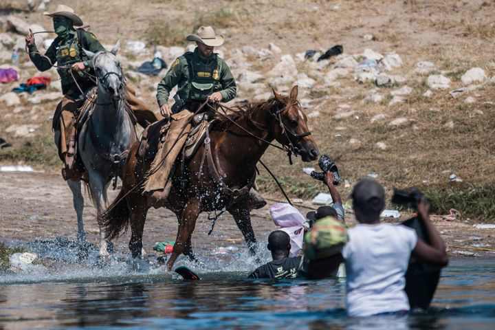 U.S. Customs and Border Protection mounted officers attempt to contain migrants as they cross the Rio Grande from Ciudad Acuñ