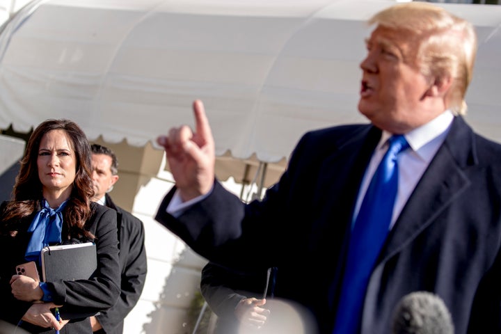 White House press secretary Stephanie Grisham, left, listens as President Donald Trump speaks to reporters at the White House on Nov. 8, 2019.