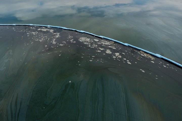 Floating barriers known as booms are used Monday to try to stop further damage in Talbert Marsh after an oil spill off Huntington Beach.