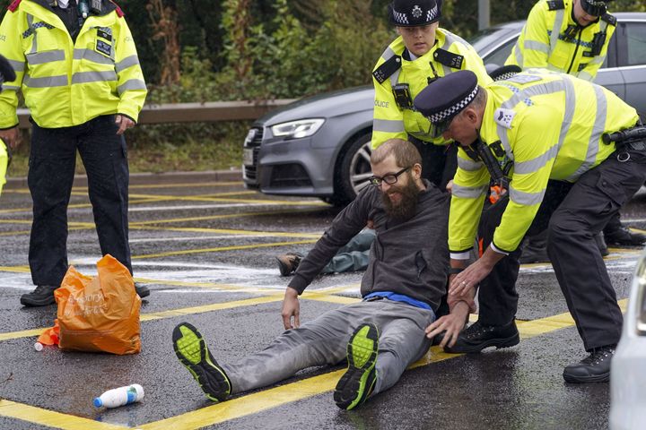 Police detain a protester from Insulate Britain occupying a roundabout leading from the M25 motorway 