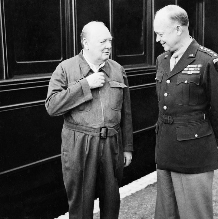 Churchill demonstrates the zipper on his famous siren suit to General Dwight D. Eisenhower during their tour of troops preparing for D Day near Lydd and Hastings in Kent in May 1944.