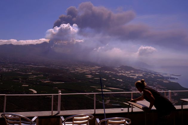 Un trabajador quita las cenizas de las mesas de un restaurantes mientras fluye la lava de un volcán en...