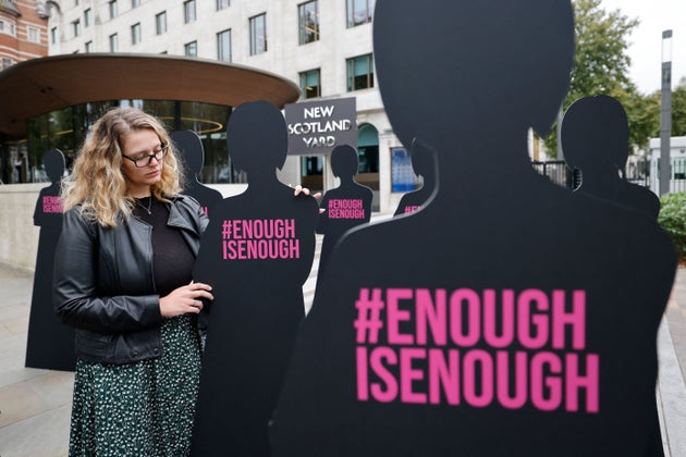 A campaigner poses with cut-out silhouettes outside the Metropolitan Police