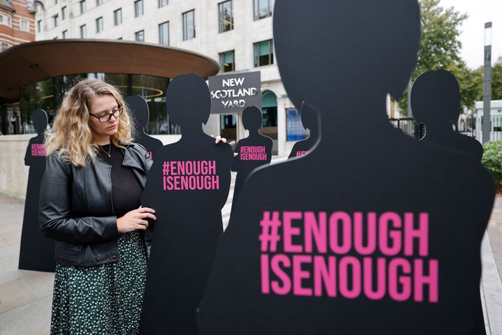 A campaigner poses with cut-out silhouettes outside the Metropolitan Police headquarters.