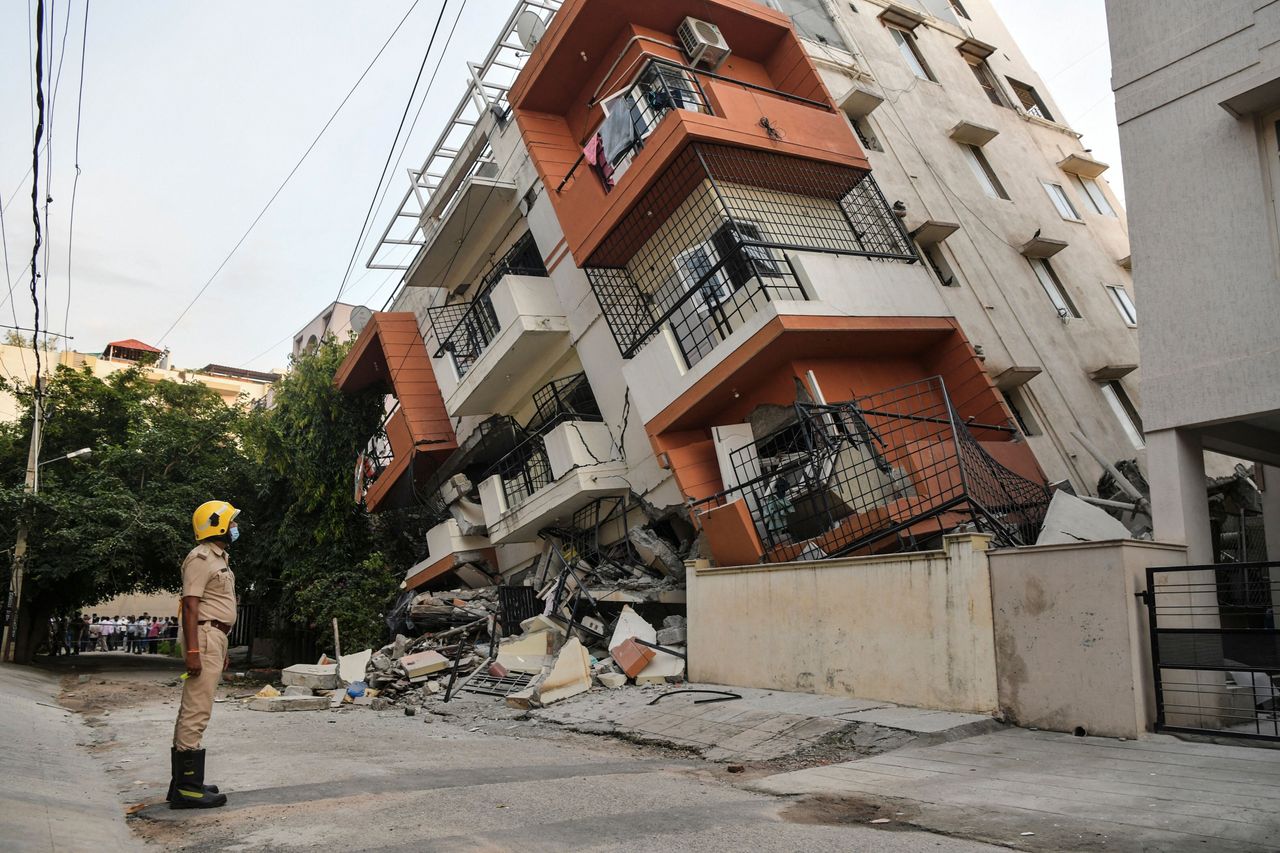 An emergency responder watches a multistory apartment building that collapsed without any reported casualties in Bangalore, India, on Oct. 7.