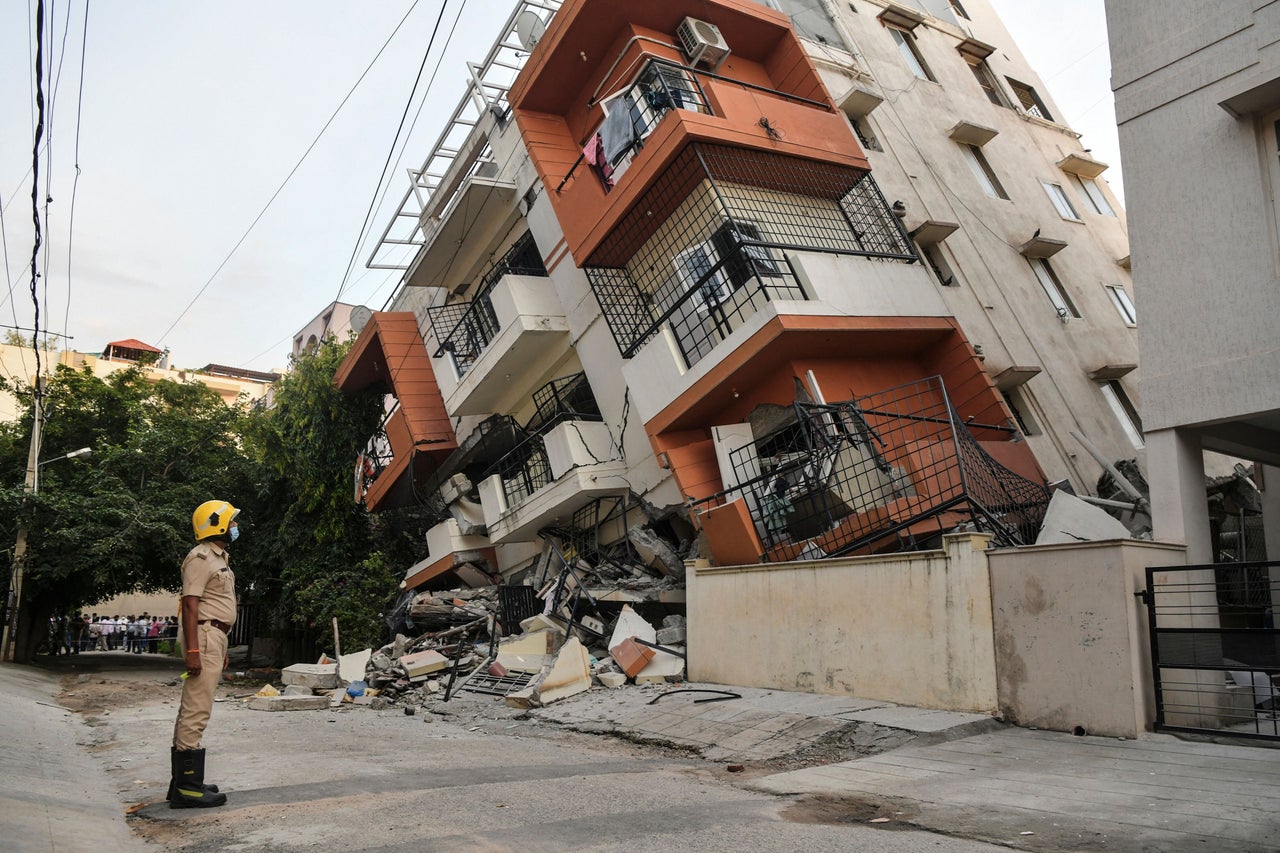 An emergency responder watches a multistory apartment building that collapsed without any reported casualties in Bangalore, India, on Oct. 7.